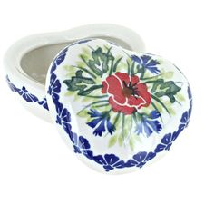 an oval shaped ceramic box with flowers painted on the front and sides, sitting on a white surface