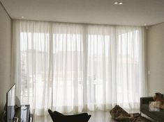 a living room with white sheer curtains and black furniture