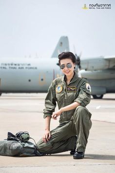 a woman in uniform kneeling on the ground next to an airplane