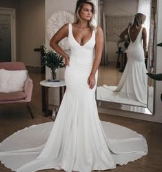 a woman standing in front of a mirror wearing a white dress