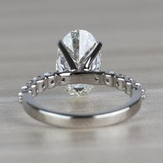 a close up view of a diamond ring on a wooden surface with the center stone missing