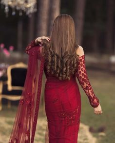 a woman with long hair wearing a red dress and holding a shawl over her shoulder