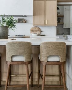 two wooden stools sitting in front of a kitchen island with white marble counter tops