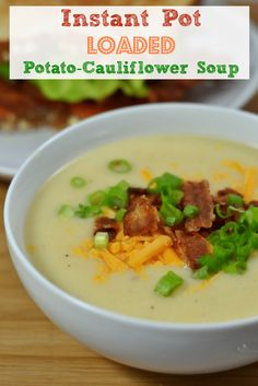 a bowl of potato soup with bacon and green onions in it on a wooden table