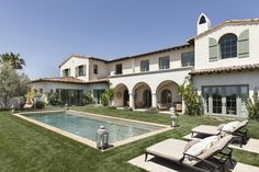 a large house with a swimming pool in the front yard and lawn furniture around it