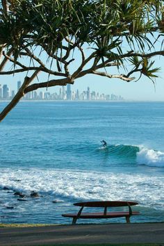 a person riding a surfboard on top of a wave in the ocean next to a bench