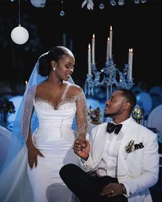 a bride and groom sitting together in front of candles