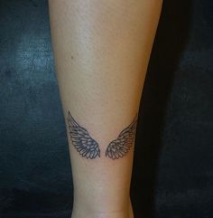 a woman's foot with an angel wing tattoo on her left ankle and right leg