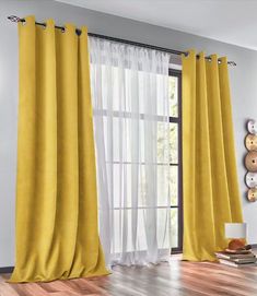 a yellow curtain hanging on the side of a window in front of a wooden floor