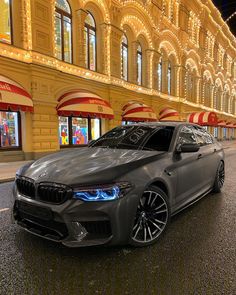 a silver car parked on the side of a road in front of a large building