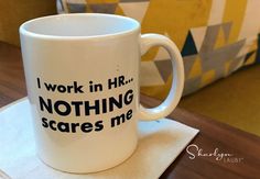 a white coffee mug with the words i work in hr nothing scares me on it