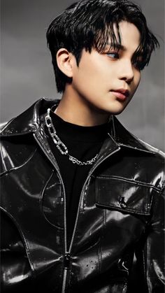 a young man with black hair wearing a leather jacket and chain around his neck is looking at the camera