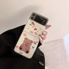 a person holding up a cell phone with a bear sticker on the back of it