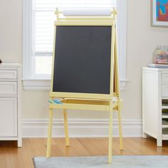 a yellow easel with a blackboard on it in front of a white wall