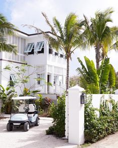 a golf cart is parked in front of a white house with palm trees on the side