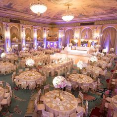 a banquet hall with tables and chairs covered in white tablecloths, decorated with floral centerpieces