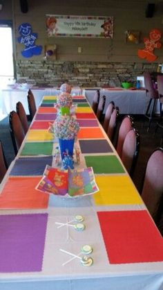 a long table is decorated with rainbow colored paper and candy bar wrappers for the centerpieces