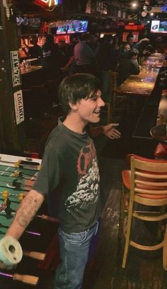 a young man standing in front of a table holding a nintendo wii game remote controller