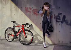 a woman standing next to a red bike near a cement wall with graffiti on it