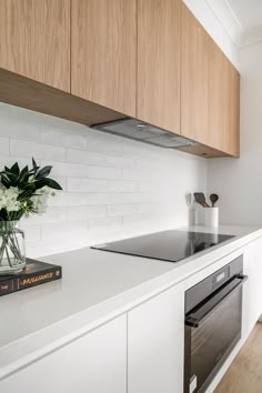 a kitchen with white counter tops and wooden cabinets next to a stove top oven under a hood