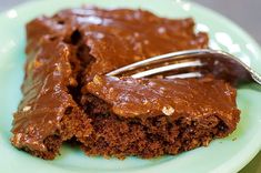 a piece of chocolate cake on a green plate with a fork in it and one slice missing