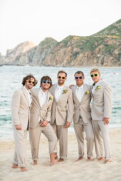 a group of men standing next to each other on top of a sandy beach