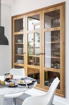 a dining room table with plates and glasses on it next to a glass door cabinet