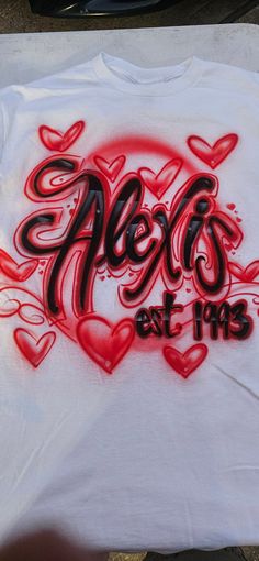 a white t - shirt with red hearts and the words mels est 1915 painted on it