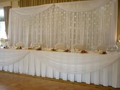 a banquet table set up with white linens and flowers on the head table for an event