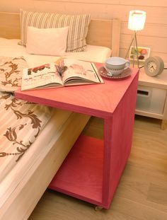 a bed with a book on top of it next to a night stand and lamp