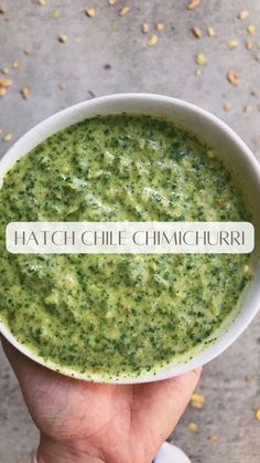 a hand holding a bowl of green soup with the words hatch chile chimica on it