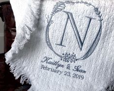 a white blanket with a monogrammed wedding date on it, and a personalized towel