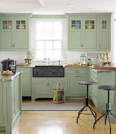 a kitchen with green cabinets and white walls, an island in the middle has a basket on it