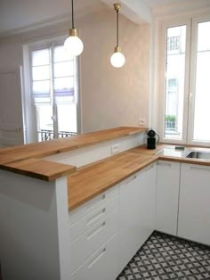 an empty kitchen with white cabinets and wood counter tops