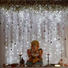 an idol sitting in front of a curtain with lights on it and decorations hanging from the ceiling