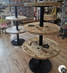 three tiered wooden table in a store with black metal legs and round wood shelves