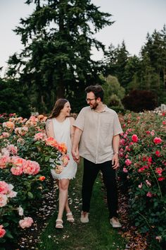 a man and woman holding hands walking through flowers