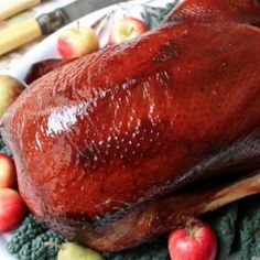 a large turkey sitting on top of a white plate next to apples and carrots