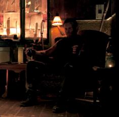 a man sitting in a chair next to a fire place with a lit candle on it