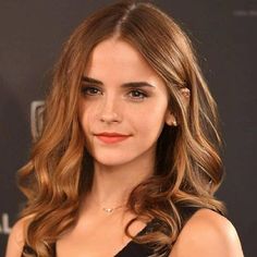 a woman with long brown hair wearing a black dress and red lipstick is posing for the camera