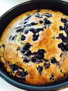 a blueberry cake in a black pan on a white counter top, ready to be eaten