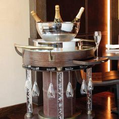 a table with wine bottles and glasses on it in front of a mirror that is hanging from the wall