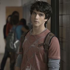 a young man standing next to a brick wall