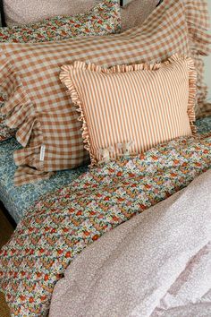 a bed topped with lots of pillows next to a pillow on top of a wooden headboard