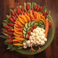 a turkey made out of veggies and carrots on a green platter