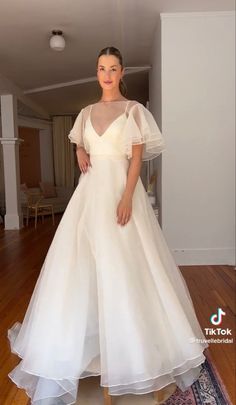 a woman in a white dress standing on a wooden floor