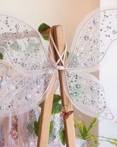 a close up of a wooden stick with a butterfly on it's wings and flowers in the background