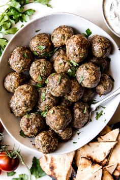 a white bowl filled with meatballs next to pita chips