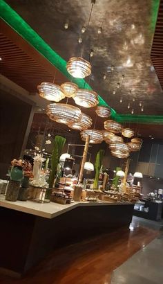 the interior of a restaurant with green lighting and chandeliers hanging from the ceiling