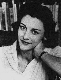 a black and white photo of a woman sitting in front of a bookshelf